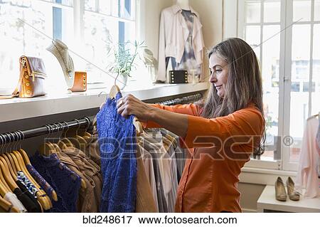 Stock Photo - Caucasian woman shopping in clothing store. Fotosearch