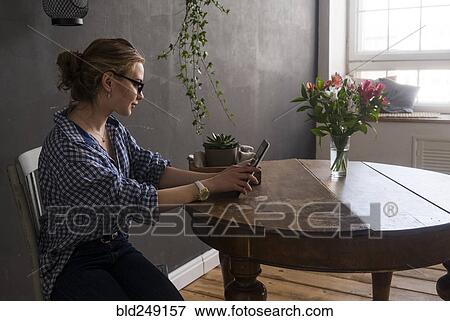 Stock Photo - Caucasian woman sitting at table using digital tablet. Fotosearch