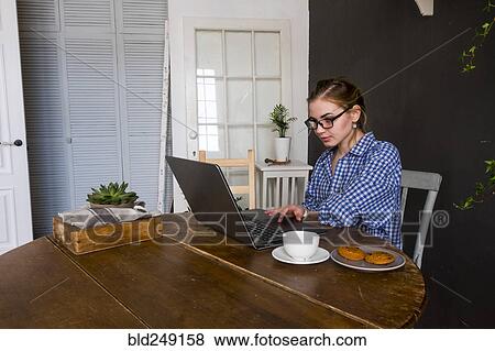 Caucasian woman sitting at table using laptop View Large Photo Image Stock Photo - Caucasian woman sitting at table using laptop. Fotosearch