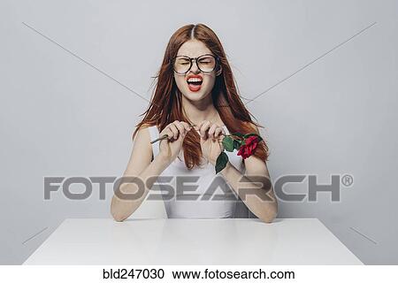 Caucasian woman sitting at windy table snapping stem of rose View Large Photo Image Stock Image - Caucasian woman sitting at windy table snapping stem of rose. Fotosearch