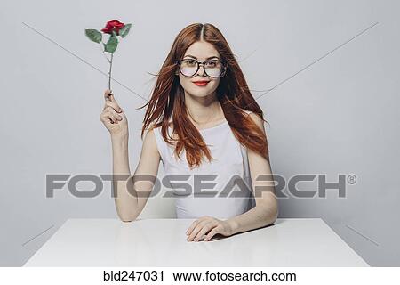 Caucasian woman sitting at windy table holding rose View Large Photo Image Stock Image - Caucasian woman sitting at windy table holding rose. Fotosearch