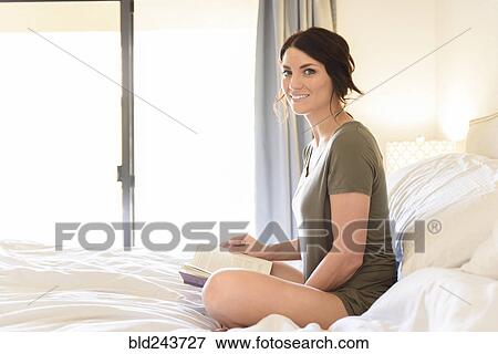 Caucasian woman sitting in bed reading book View Large Photo Image Stock Photo - Caucasian woman sitting in bed reading book. Fotosearch