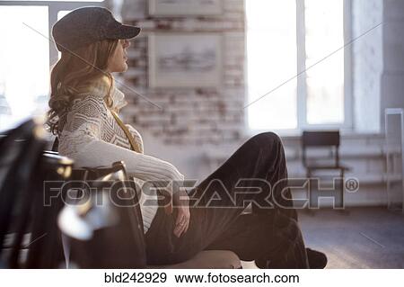 Stock Photo - Caucasian woman sitting in chair with legs crossed. Fotosearch