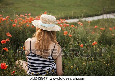 Stock Photo - Caucasian woman sitting in wildflowers. Fotosearch