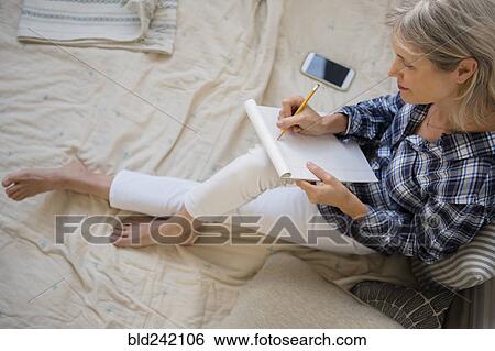 Caucasian woman sitting on bed writing on cell phone View Large Photo Image Stock Photograph - Caucasian woman sitting on bed writing on cell phone. Fotosearch