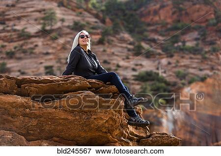 Stock Photo - Caucasian woman sitting on edge of rock. Fotosearch