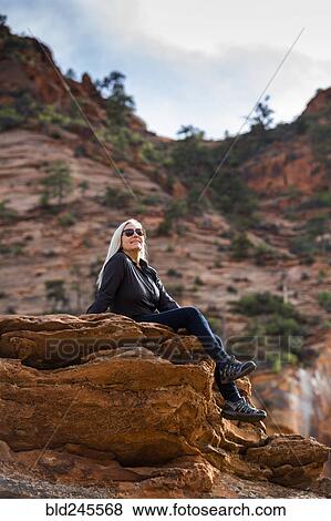Caucasian woman sitting on edge of rock View Large Photo Image Stock Photo - Caucasian woman sitting on edge of rock. Fotosearch