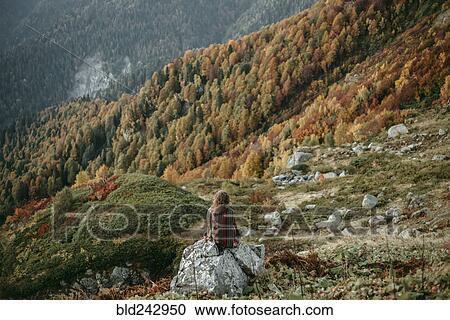 Caucasian woman sitting on mountain rock overlooking valley View Large Photo Image Stock Image - Caucasian woman sitting on mountain rock overlooking valley. Fotosearch