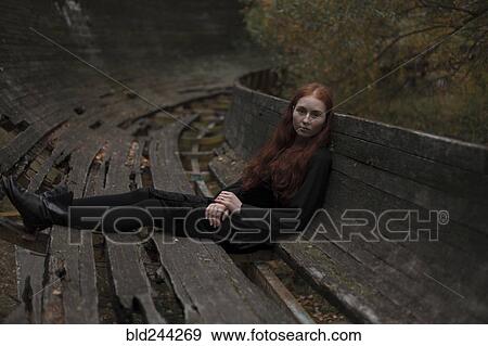 Stock Photo - Caucasian woman sitting on rotting wooden bench. Fotosearch