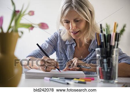 Caucasian woman sketching on pile of paper View Large Photo Image Stock Photo - Caucasian woman sketching on pile of paper. Fotosearch