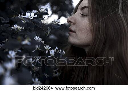 Picture - Caucasian woman smelling flowers outdoors. Fotosearch