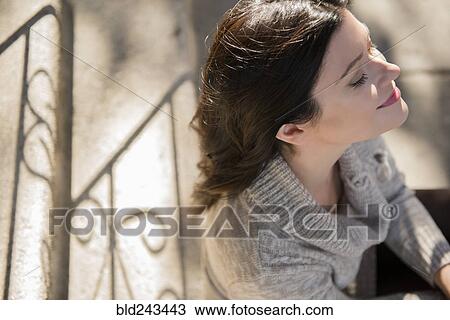 Stock Image - Caucasian woman smiling on staircase. Fotosearch