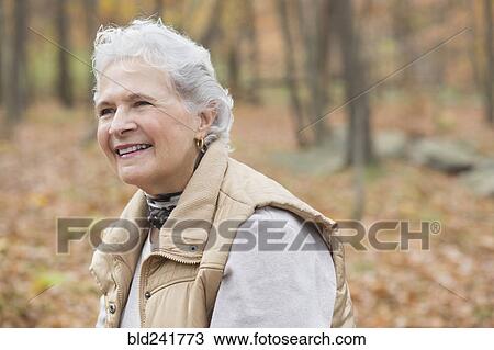Stock Image - Caucasian woman smiling outdoors in autumn. Fotosearch