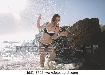 Caucasian woman splashing in ocean waves View Large Photo Image Stock Image - Caucasian woman splashing in ocean waves. Fotosearch