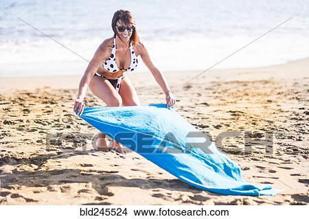 Caucasian woman spreading blanket on beach View Large Photo Image Picture - Caucasian woman spreading blanket on beach. Fotosearch