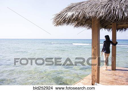 Picture - Caucasian woman standing at edge of dock. Fotosearch