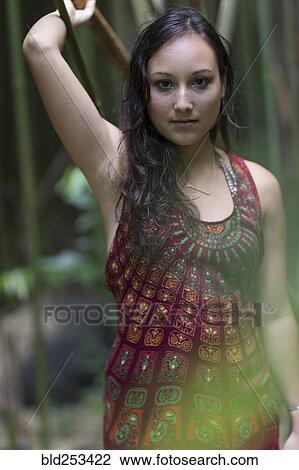 Stock Image - Caucasian woman standing in bamboo forest. Fotosearch