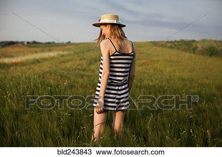 Stock Image - Caucasian woman standing in field of tall grass. Fotosearch
