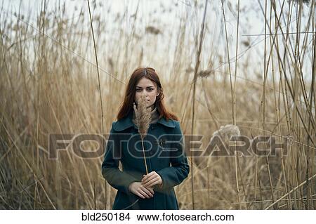 Caucasian woman standing in field holding stalk of grass View Large Photo Image Picture - Caucasian woman standing in field holding stalk of grass. Fotosearch