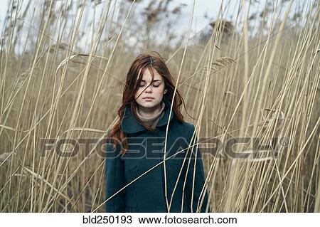 Stock Image - Caucasian woman standing in field with eyes closed. Fotosearch