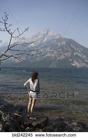 Stock Photography - Caucasian woman standing in Jenny Lake admiring Great Teton mountains, Wyoming, United States. Fotosearch