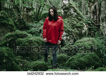 Stock Image - Caucasian woman standing in lush forest. Fotosearch
