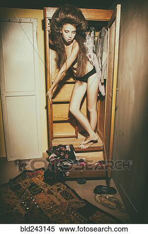 Stock Photography - Caucasian woman standing in wardrobe wearing underwear. Fotosearch