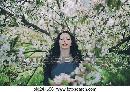 Stock Photograph - Caucasian woman standing near flowering tree. Fotosearch