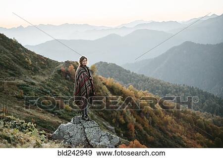 Caucasian woman standing on mountain rock overlooking valley View Large Photo Image Stock Photo - Caucasian woman standing on mountain rock overlooking valley. Fotosearch