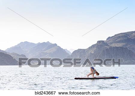 Caucasian woman stretching on paddleboard in river View Large Photo Image Stock Photo - Caucasian woman stretching on paddleboard in river. Fotosearch