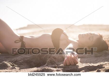 Stock Photography - Caucasian woman sunbathing on beach. Fotosearch