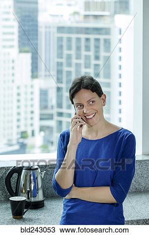 Caucasian woman talking on cell phone near window View Large Photo Image Stock Image - Caucasian woman talking on cell phone near window. Fotosearch