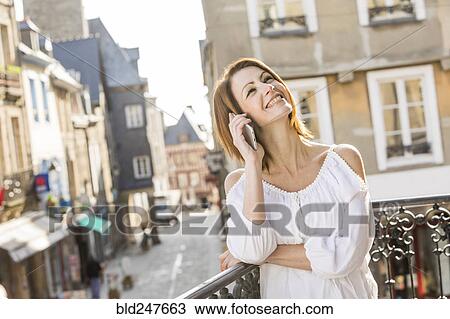 Stock Image - Caucasian woman talking on telephone in city. Fotosearch