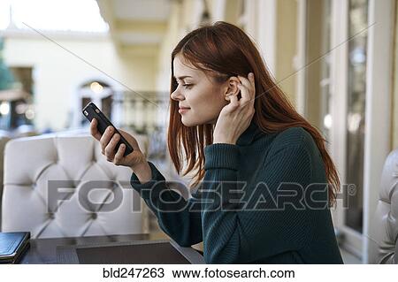 Stock Image - Caucasian woman texting on cell phone at restaurant. Fotosearch