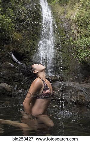 Stock Photo - Caucasian woman tossing hair under waterfall. Fotosearch