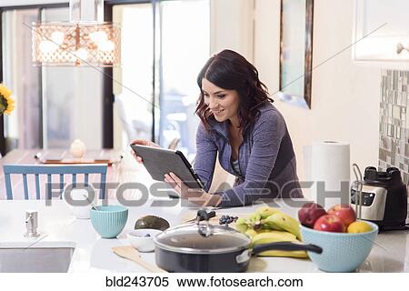 Caucasian woman using digital tablet in domestic kitchen View Large Photo Image Stock Photography - Caucasian woman using digital tablet in domestic kitchen. Fotosearch
