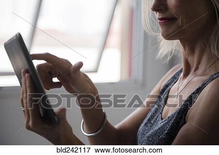 Caucasian woman using digital tablet near window View Large Photo Image Stock Photo - Caucasian woman using digital tablet near window. Fotosearch