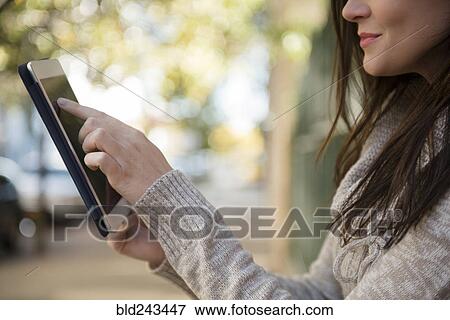 Caucasian woman using digital tablet outdoors View Large Photo Image Stock Photo - Caucasian woman using digital tablet outdoors. Fotosearch