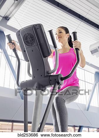 Caucasian woman using elliptical machine in gymnasium View Large Photo Image Stock Photograph - Caucasian woman using elliptical machine in gymnasium. Fotosearch