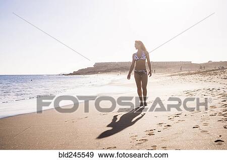 Stock Photo - Caucasian woman walking on beach. Fotosearch