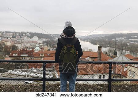 Stock Image - Caucasian woman wearing backpack admiring scenic view of city. Fotosearch