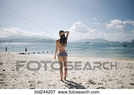 Stock Photo - Caucasian woman wearing bikini at beach. Fotosearch