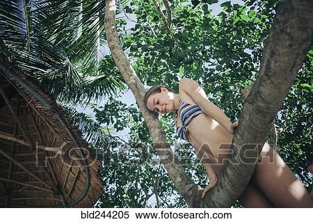 Stock Photography - Caucasian woman wearing bikini climbing tree. Fotosearch