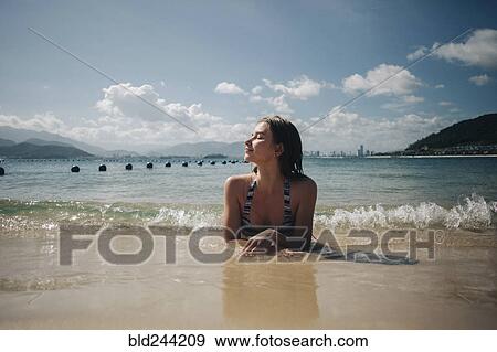 Caucasian woman wearing bikini laying in waves on beach View Large Photo Image Stock Photo - Caucasian woman wearing bikini laying in waves on beach. Fotosearch