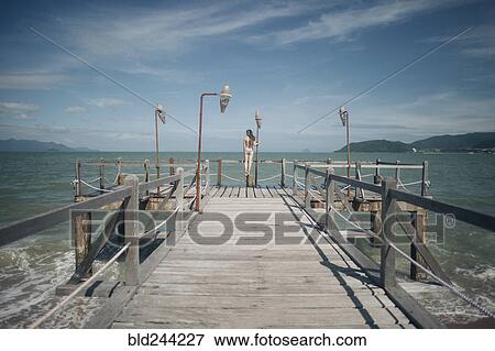 Caucasian woman wearing bikini standing on railing on dock View Large Photo Image Stock Photo - Caucasian woman wearing bikini standing on railing on dock. Fotosearch
