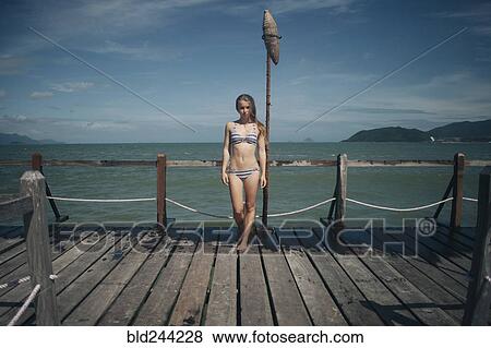 Stock Photo - Caucasian woman wearing bikini standing on dock. Fotosearch