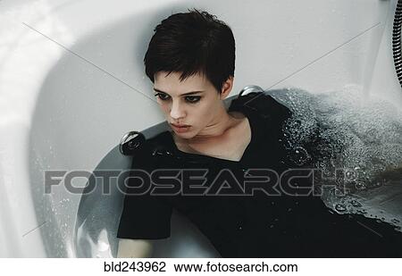 Stock Image - Caucasian woman wearing dress in bathtub. Fotosearch
