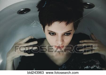 Stock Image - Caucasian woman wearing dress in bathtub. Fotosearch