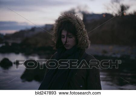 Stock Image - Caucasian woman wearing fur hood at ocean. Fotosearch
