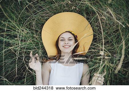 Caucasian woman wearing hat laying in grass View Large Photo Image Stock Photo - Caucasian woman wearing hat laying in grass. Fotosearch